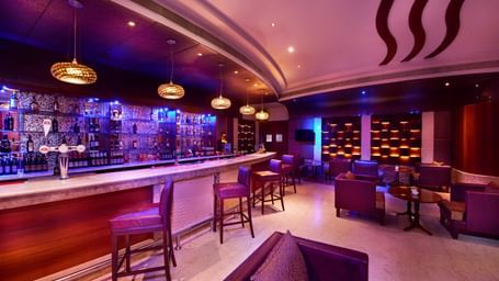 An image of a restro bar with chairs and table set with dim lighting at Accord Puducherry